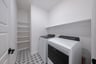 laundry room with tile floors, white shelves, washer, and dryer