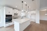 open kitchen with white cabinets and island pendants