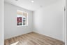 bedroom with wood floors, white walls, and window looking out to the front covered porch