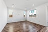 great room with wood floors, white walls, three windows looking out to the backyard, and recessed ceiling lights