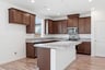 kitchen with brown wood cabinets, island with granite counters, window, and stainless steel appliances