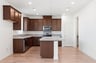 kitchen with wood floors, brown wood cabinets, island, granite counters, and recessed ceiling lights