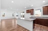 kitchen with brown wood cabinets, granite counters, wood floors, island, and window above sink