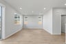 great room with light gray walls, three windows, and light wood floors