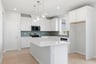 kitchen with white cabinets, white quartz counters, green tile backsplash, island, and window above sink