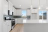 kitchen with white cabinets, white quartz counters, green tile backsplash, and window above sink