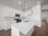 kitchen with quartz countertops, pendant lighting & white cabinets