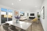 great room with wood floors, white dining table with four tan chairs, white sofa, two yellow accent chairs, and multiple windows