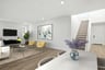 great room with wood floors, two yellow accent chairs, television on wall, and modern wall art