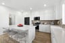 kitchen with wood floors, white cabinets & counters, tan tile backsplash, island, and walk-in pantry with shelves