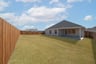 covered patio that opens up to fenced backyard 