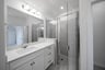 bathroom with walk-in shower with white cabinets 