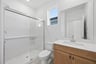 bathroom with light wood cabinets, white counters, walk-in shower, and window above toilet