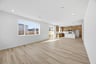 great room with light wood floors, white walls, large window looking out to backyard, and recessed ceiling lights