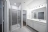primary bathroom with walk-in shower and white cabinets