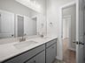 bathroom with dual sinks, quartz countertops & white cabinets