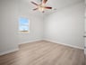 bedroom with brown flooring, window & a ceiling fan