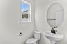 powder room with a window and oval mirror