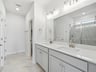 primary bath with dual sinks, white tile and pendant lighting