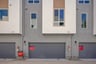 rear exterior of gray condo building with windows and two-car garage