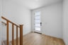 entry foyer with white walls, wood floor, and staircase leading upstairs