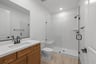 bathroom with tan tile floors, wood cabinets, white counters, and large walk-in shower with bench