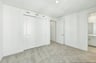 bedroom with tan carpet, white walls, and view of attached bathroom