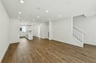 great room with wood floors, white walls, recessed ceiling lights, and view of kitchen with white cabinets