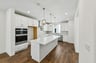 kitchen with wood floors, white cabinets & counters, white walls, and window