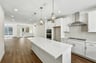 kitchen with white cabinets & counters, wood floors, and three hanging pendant lights over island