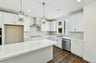 kitchen with white cabinets & counters, wood floors, island, stainless steel appliances, and window above sink