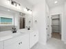bathroom with dual sinks, quartz countertops and pendant lighting