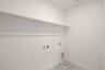 laundry room with tile floors and white shelf