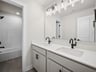bathroom with dual sinks, quartz countertops & a bathtub