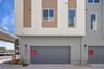 back exterior of gray and white condo building showing two-car attached garages
