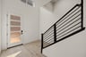 entry foyer with light wood floors, glass front door, and black modern stair rail