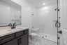 bathroom with black cabinets, white counters, and large walk-in shower with glass enclosure