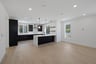 great room with white walls, light wood floors, and view of kitchen with black cabinets
