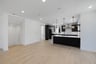 kitchen with black cabinets, white counters, light wood floors, and three light pendants above peninsula