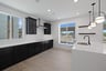 kitchen with light wood floors, black cabinets, white quartz counters, two windows, and sink in island