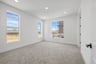 bedroom with three windows, tan carpet, and white walls