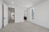 bedroom with tan carpet, white walls, window, and attached bathroom