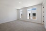 bedroom with tan carpet, two windows, and white walls