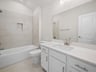 bathroom with soaking tub, quartz countertops & a sink