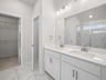 bathroom with a walk-in shower, quartz countertops & dual sinks