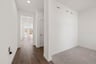 entry foyer with wood floors, white walls, and view of study with tan carpet