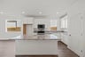 kitchen with white cabinets, granite counters, wood floors, island, and window over sink
