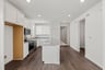 kitchen with granite counters, white cabinets, wood floors, and island
