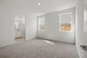 bedroom with tan carpet, white walls, two windows, and view of attached bathroom