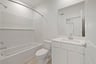 bathroom with white cabinets & counters, tan tile floor, and tub with shower overhead